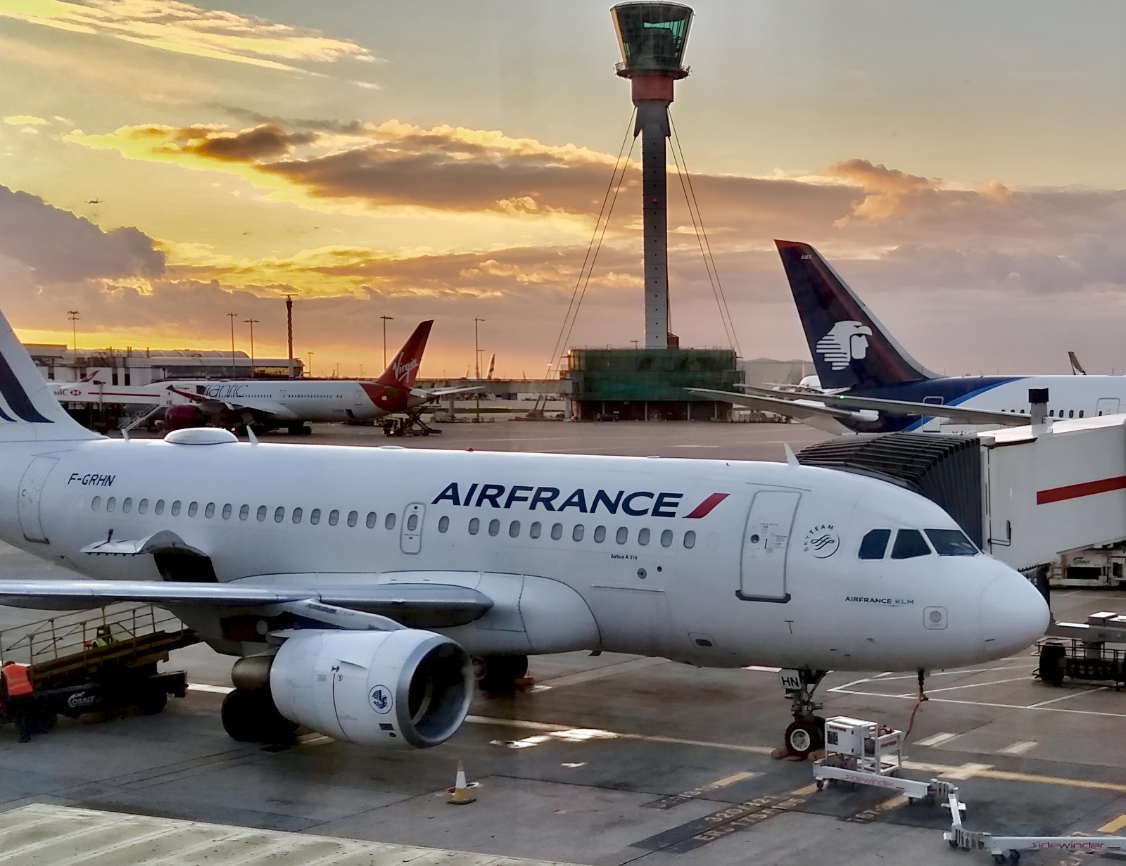 An Airbus A319 at sunset at London Heathrow Terminal 3, with the control tower behind